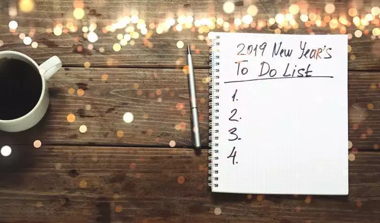 New year 2019 Goals Concept. Notepad with To do list and cup of coffee on wooden table, top view, flat lay