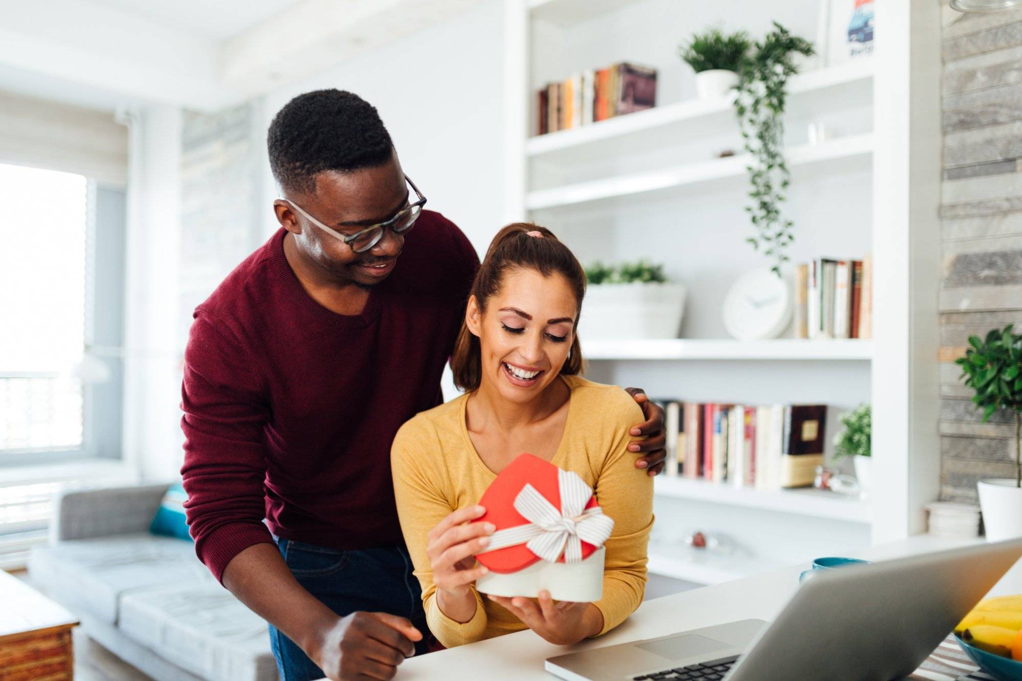 Happy young and diverse couple celebrating Valentine's day in their home