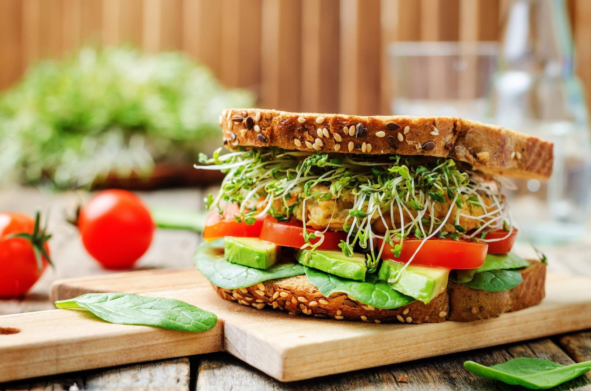 sprouts avocado tomato spinach chickpeas burger rye sandwich