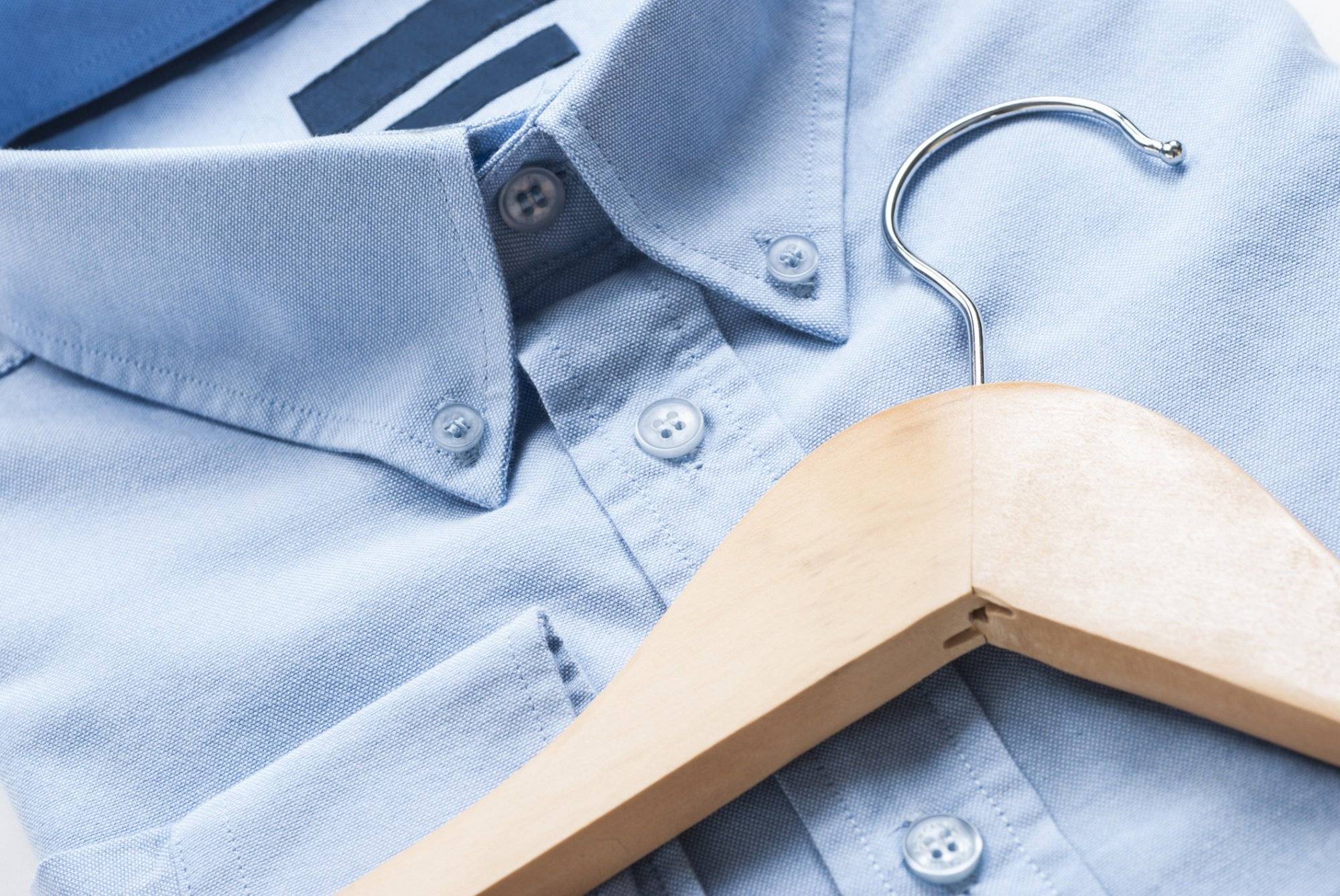 Wooden cloth hanger on top of blue shirt